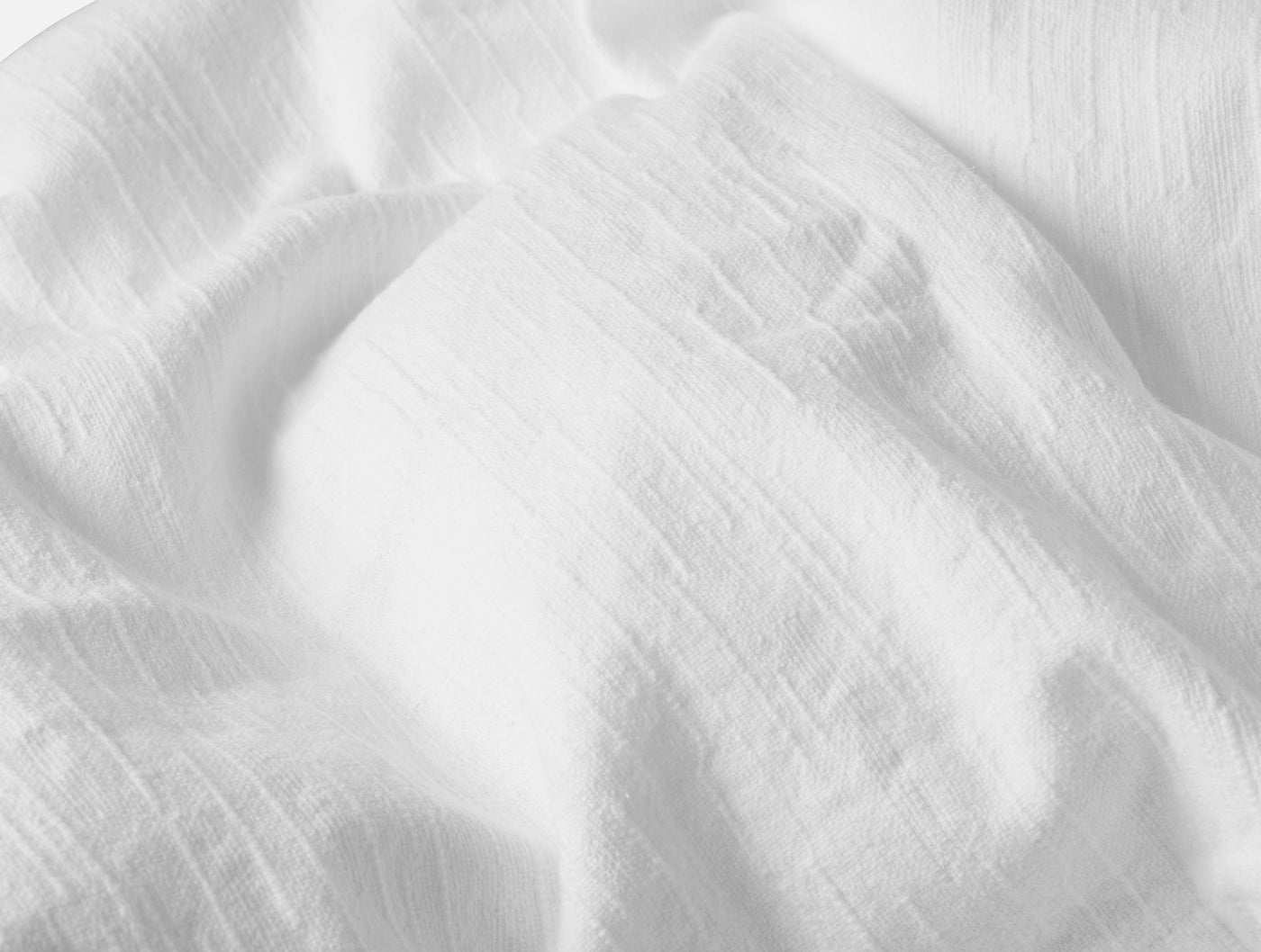 Close-up of draped white linen fabric showing soft natural wrinkle texture.