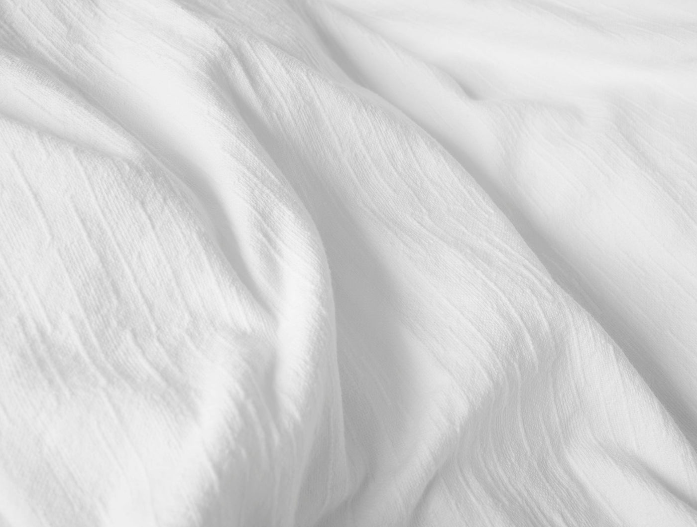 Close-up of white Coyuchi Toro Canyon linen fabric showing soft crinkled texture and natural drape.
