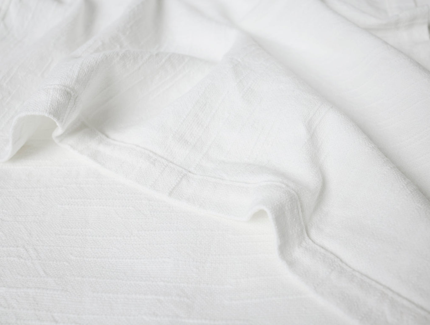 Close-up of white Coyuchi Toro Canyon napkin showing textured weave and soft drape.