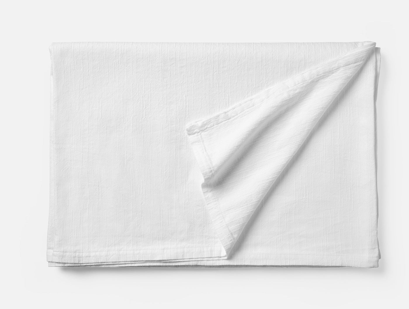 Coyuchi Toro Canyon tablecloth in white, folded to show subtle woven texture.