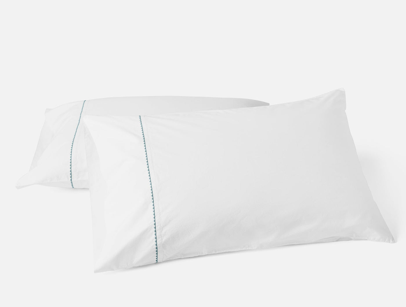 Coyuchi Trailing Embroidered pillowcase pair, white with teal embroidered trim detail.