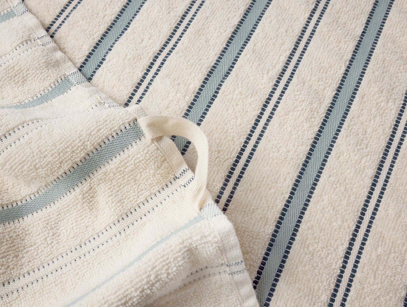 Close-up of Coyuchi Acacia hand towel loop and blue stripe detail on ivory terry.