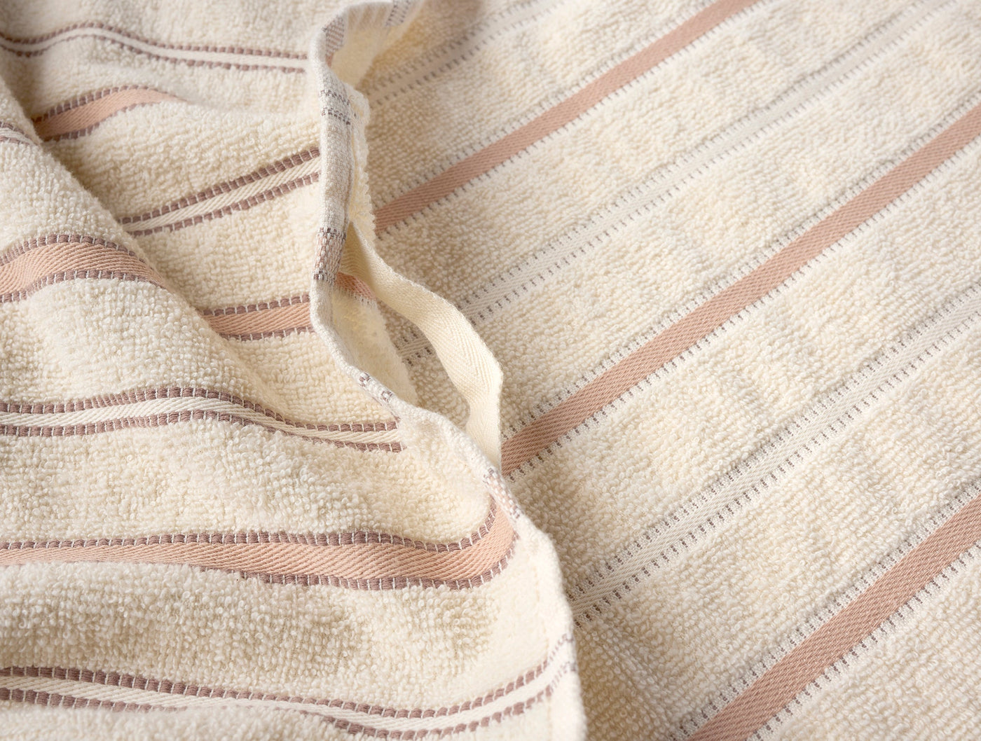 Close-up of Coyuchi Acacia hand towel texture, ivory terry with dusty rose and taupe woven stripes.