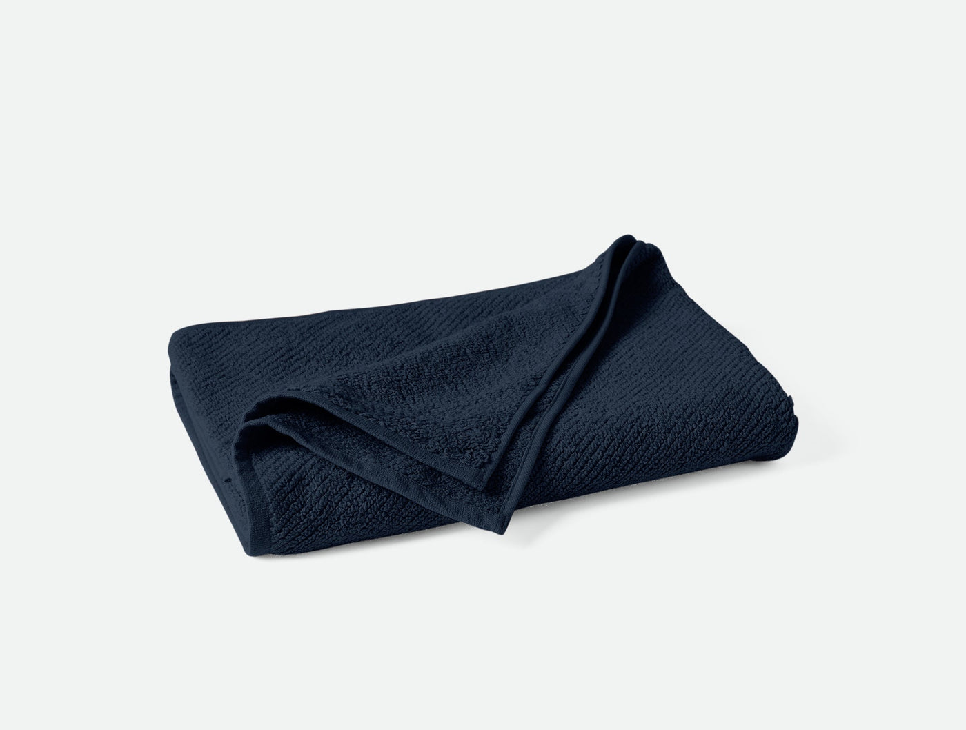 Navy blue folded Coyuchi Air Weight towel showing textured weave detail.