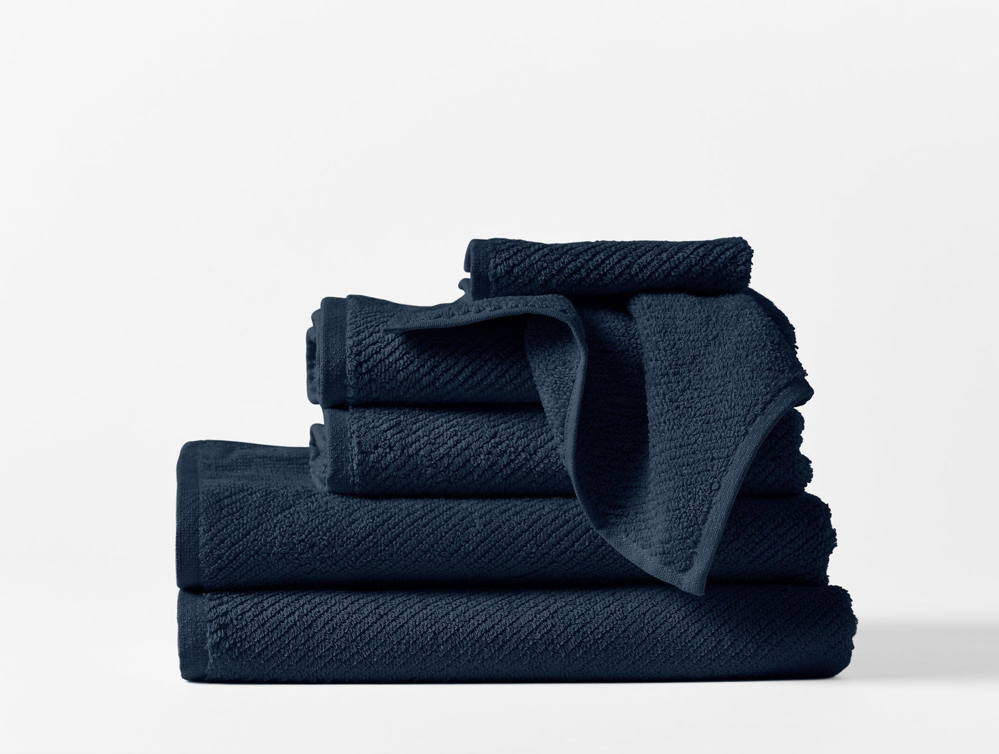 Navy blue Coyuchi Air Weight towel set stacked, showing textured waffle weave detail.