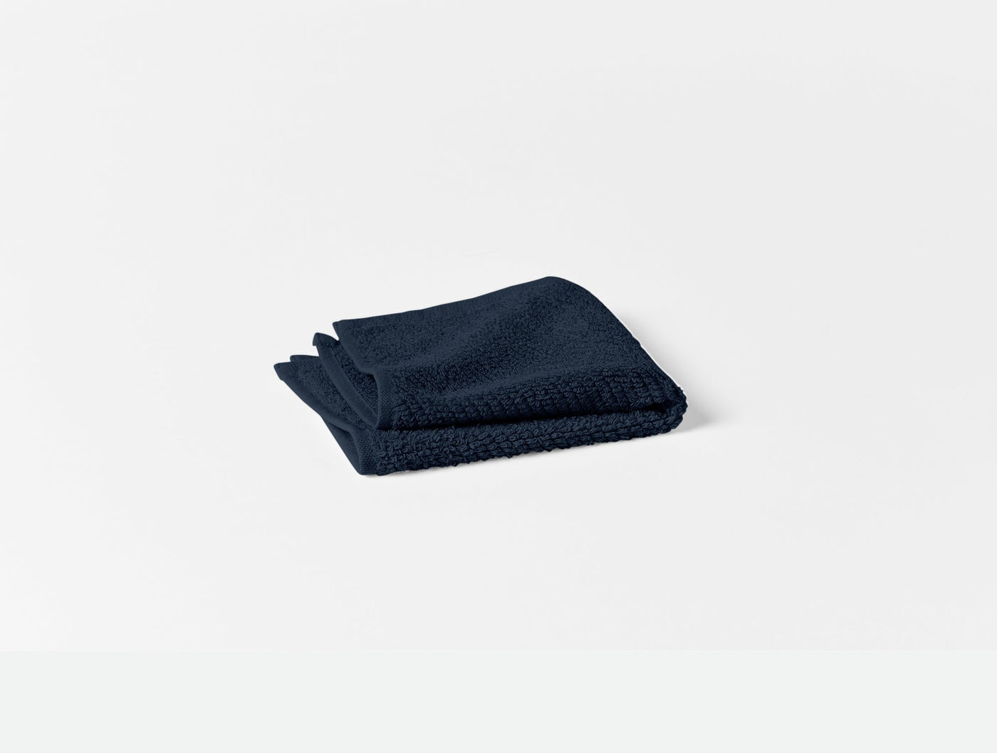 Close-up of folded navy Coyuchi Air Weight bath towel showing textured waffle weave.