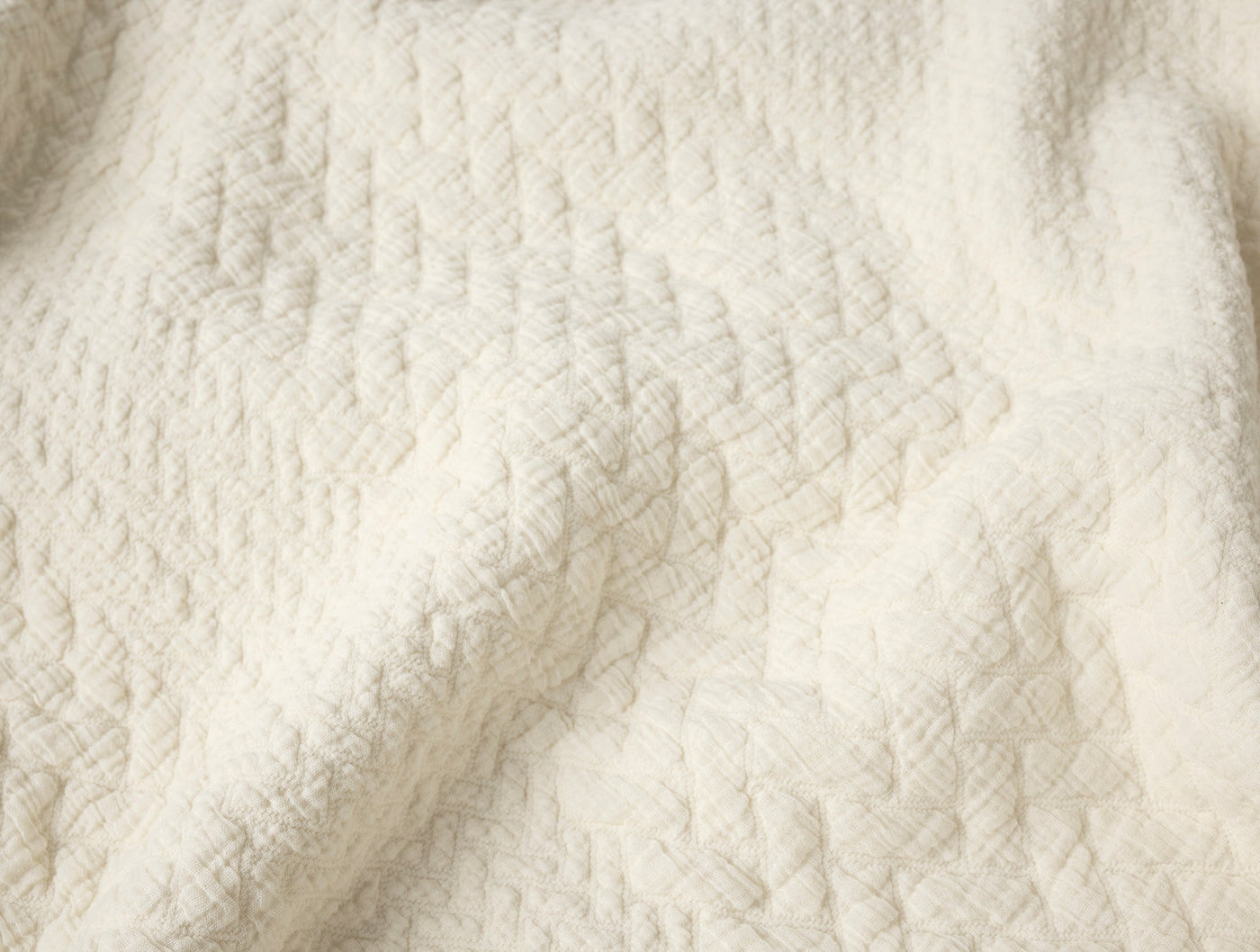 Close-up of ivory matelassé weave texture on Coyuchi Angeles blanket.