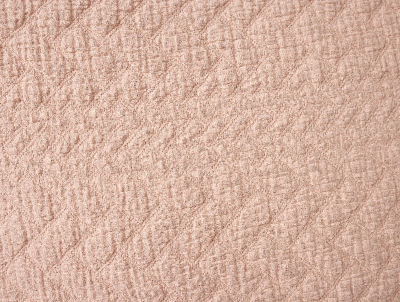 Close-up of blush matelasse weave with diagonal diamond quilting pattern.