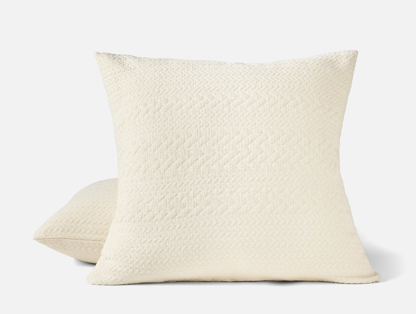 Pair of ivory Coyuchi Angeles Matelassé shams showing quilted diamond-weave texture.
