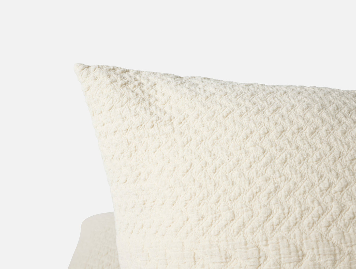 Close-up corner of ivory matelassé pillow sham showing chevron-textured weave detail.