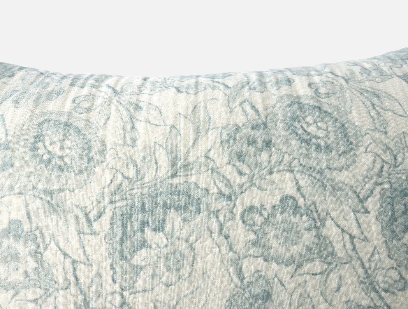 Close-up of Coyuchi Balboa Matelasse muted blue floral print on ivory linen pillow cover.