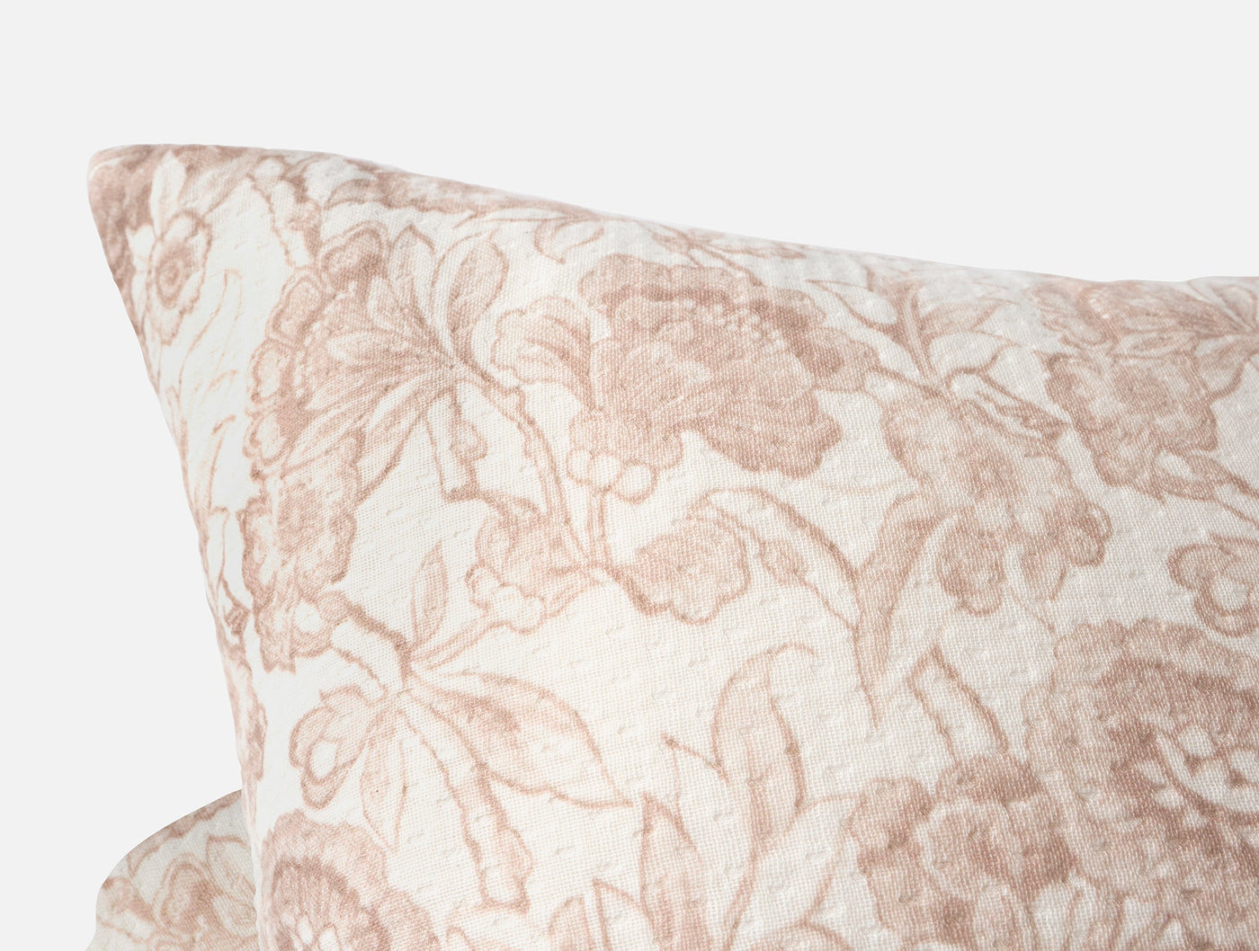 Close-up of Coyuchi Balboa Matelasse pillow corner, dusty rose floral print on ivory.