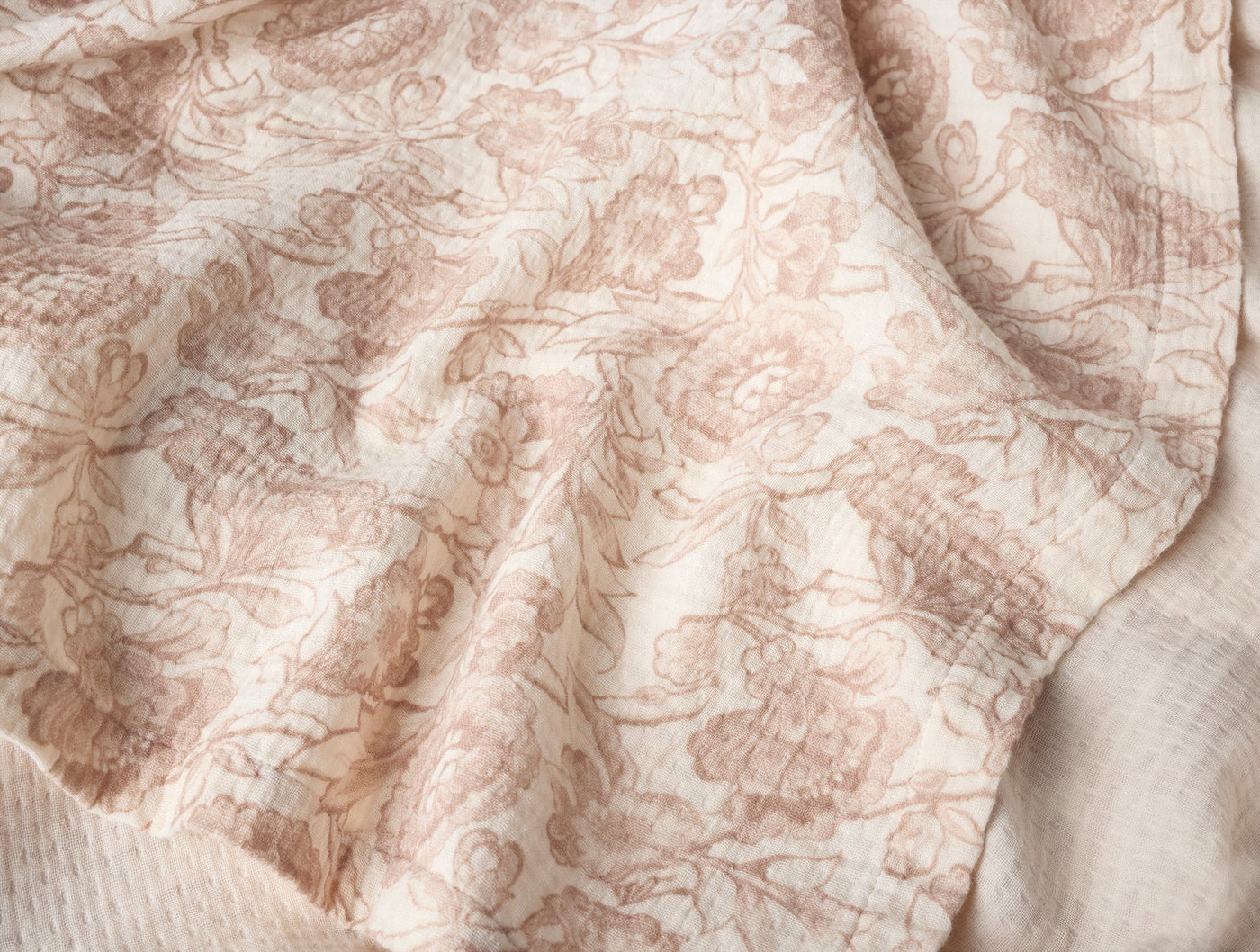 Close-up of Coyuchi Balboa throw, ivory fabric with dusty rose floral toile print.
