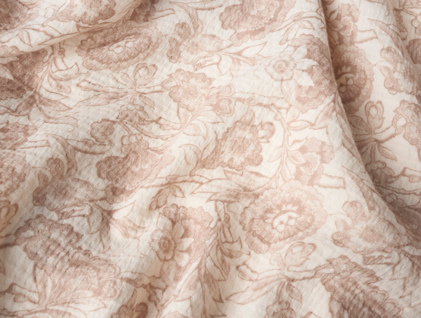 Close-up of ivory matelassé fabric with rose floral toile print and quilted texture.
