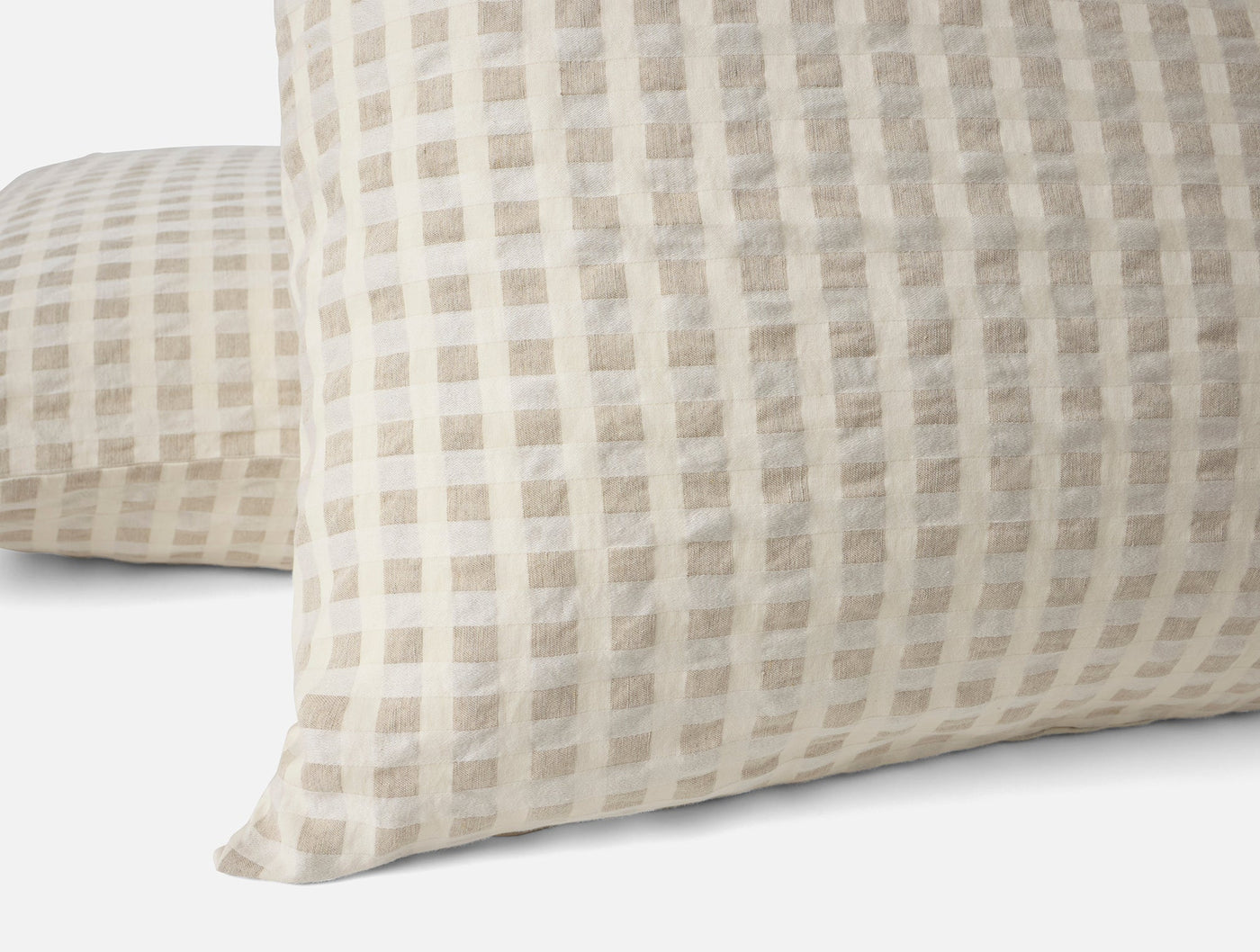 Close-up of Coyuchi Birch pillow shams in natural with woven gingham check pattern.