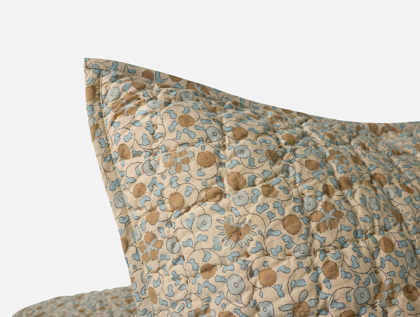 Close-up of Coyuchi Blossom Handstitched sham corner, dusty blue and tan floral print.