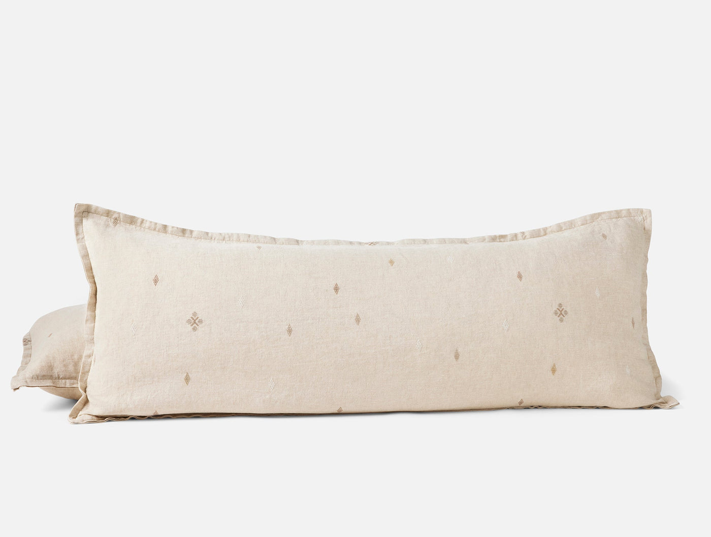 Coyuchi Cambria long lumbar pillow in natural linen with small embroidered diamond motifs.