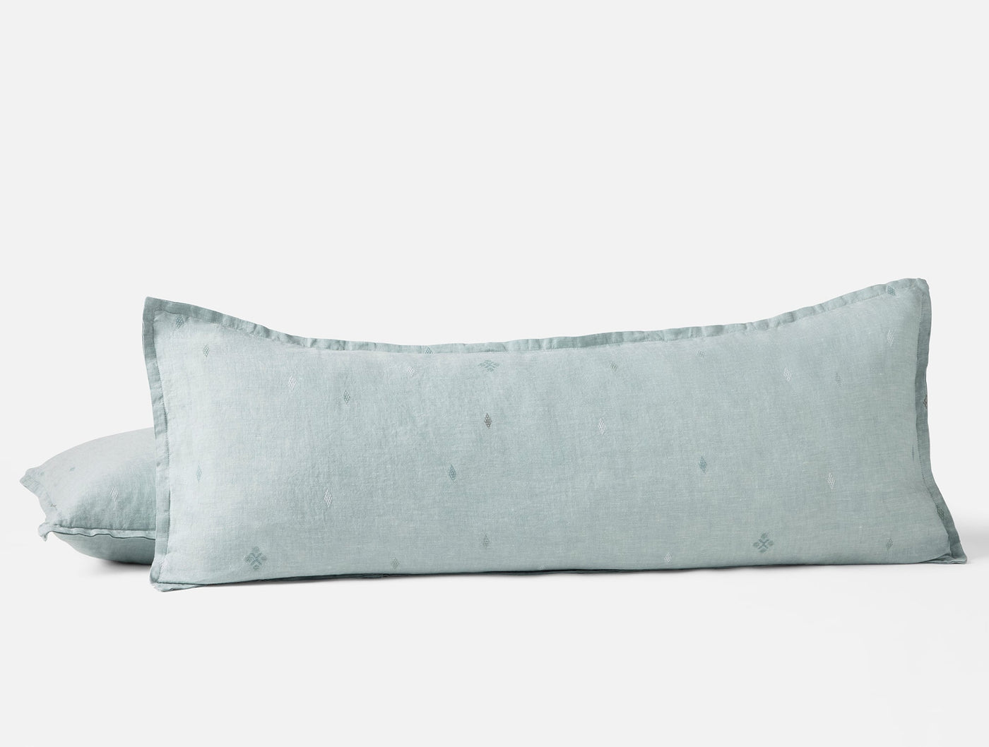 Sage linen bolster and standard pillow with subtle diamond embroidery and flange trim.