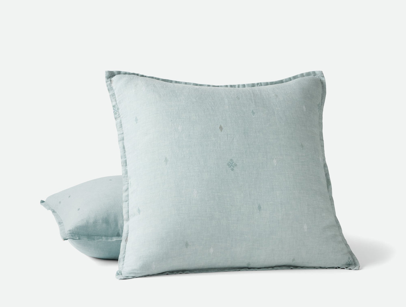 Two Coyuchi Cambria linen pillows stacked, pale aqua with subtle embroidered dot motif.