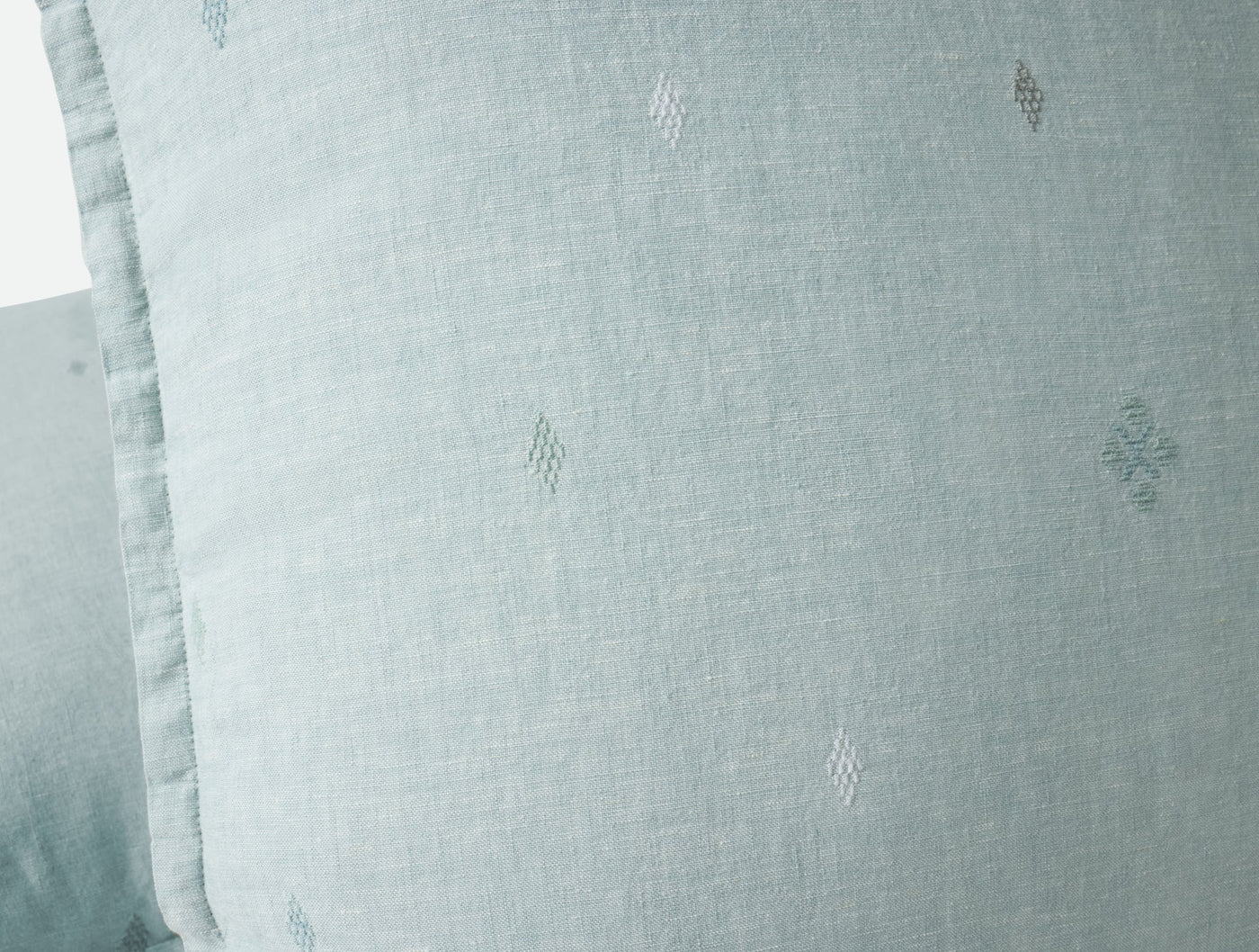 Close-up of Coyuchi Cambria pillow in mist, showing diamond embroidery on soft linen.