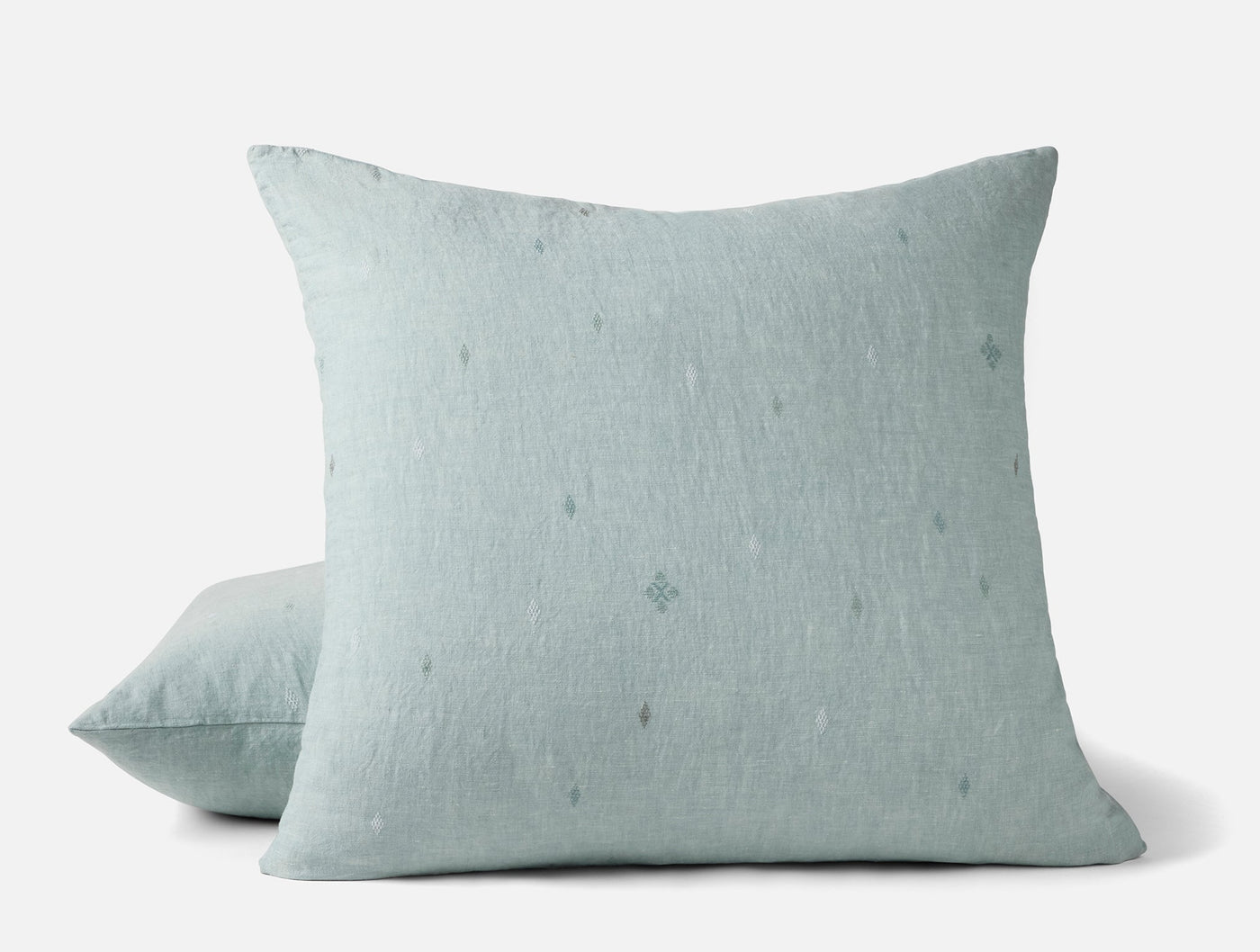 Close-up of Coyuchi Cambria sage linen sham pair showing embroidered diamond motifs.
