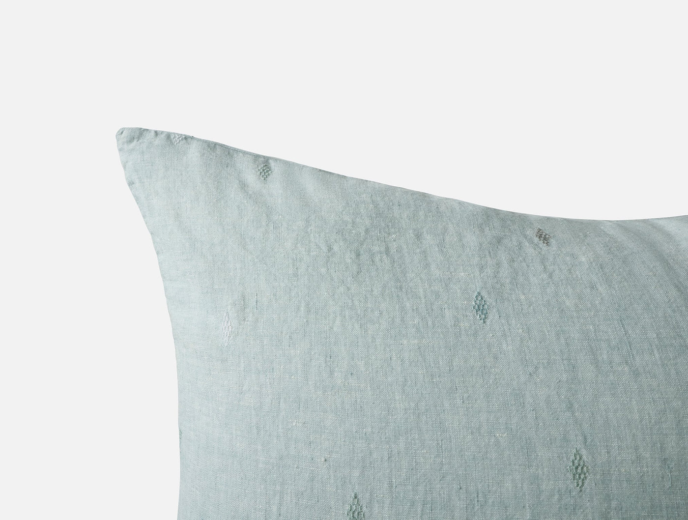 Close-up corner of Coyuchi Cambria sham in mist, showing embroidered dot detail on linen.