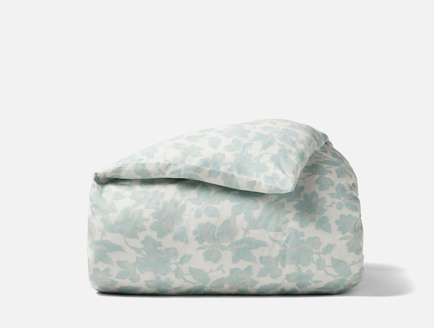 Coyuchi Camellia Print duvet cover folded, showing soft blue floral pattern on ivory ground.