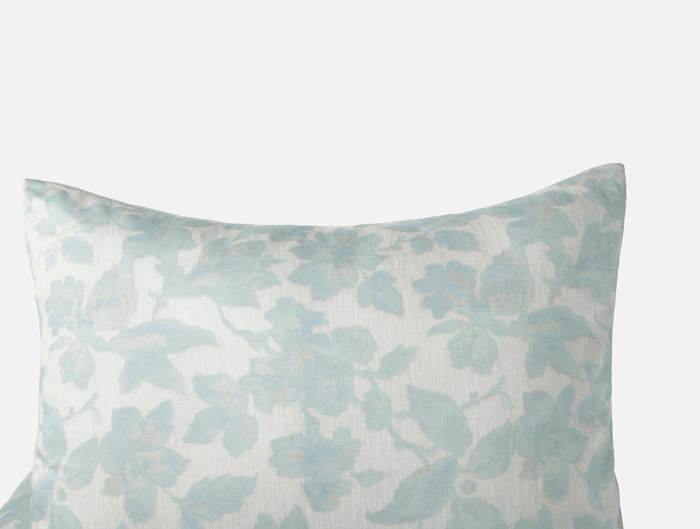 Close-up corner of Coyuchi Camellia Print sham in soft aqua floral on ivory ground.