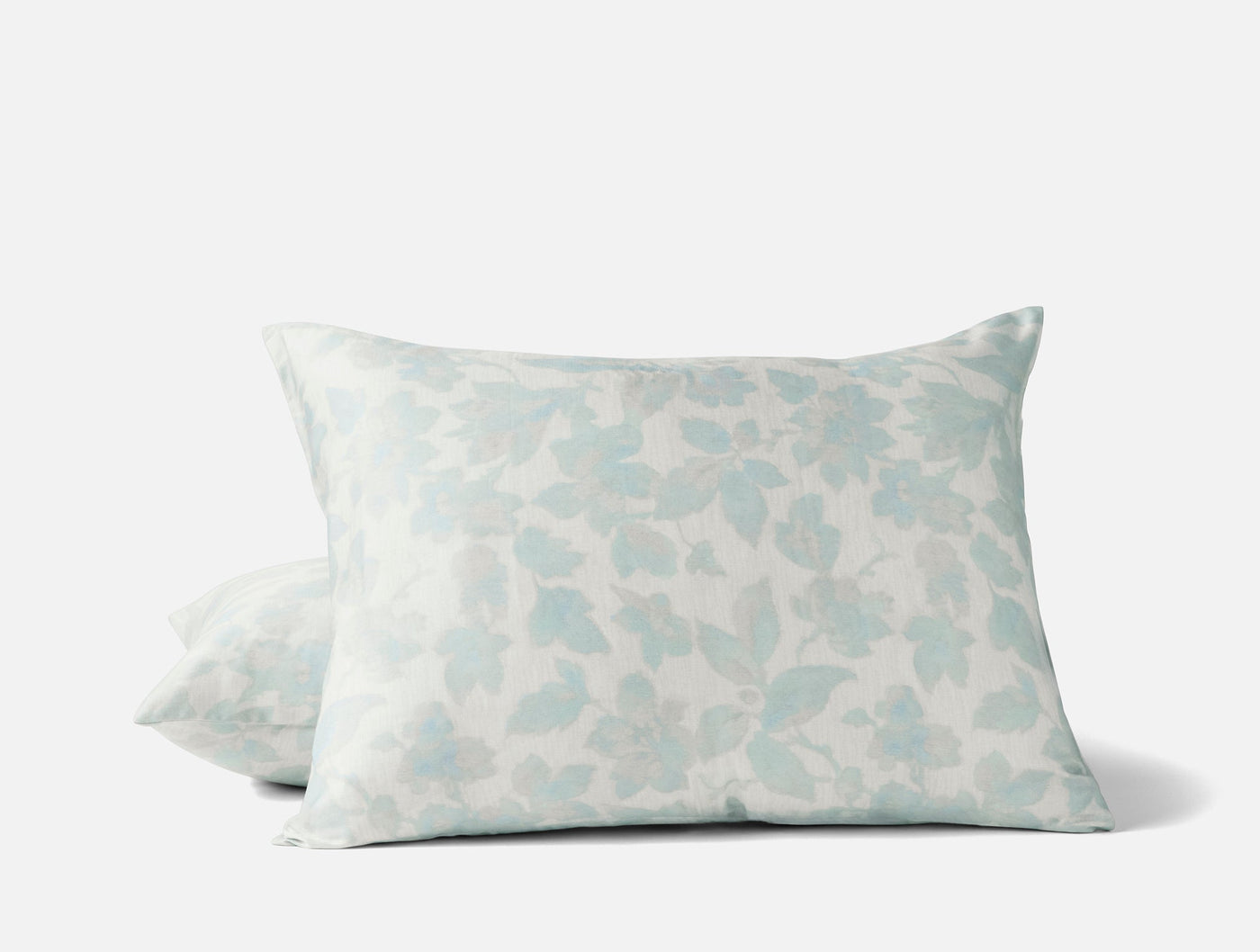 Two Coyuchi Camellia Print shams stacked, seafoam floral pattern on ivory ground.