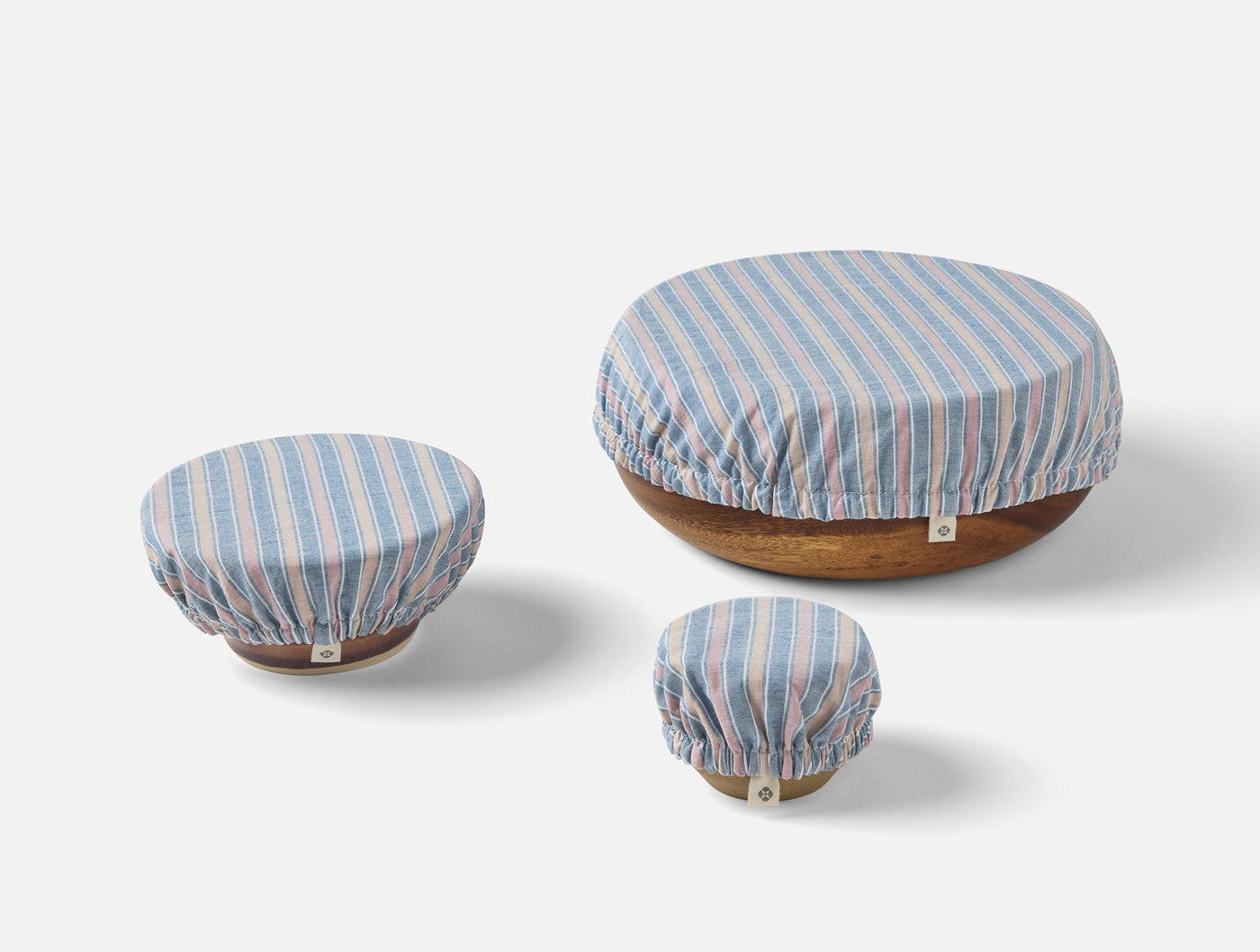 Three Coyuchi Conserve bowl covers in blue and pink stripe, sized small to large.