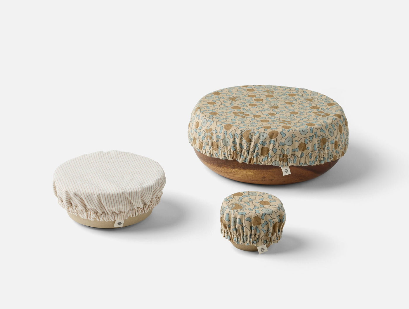 Three Coyuchi Conserve bowl covers in varying sizes, floral and stripe patterns.