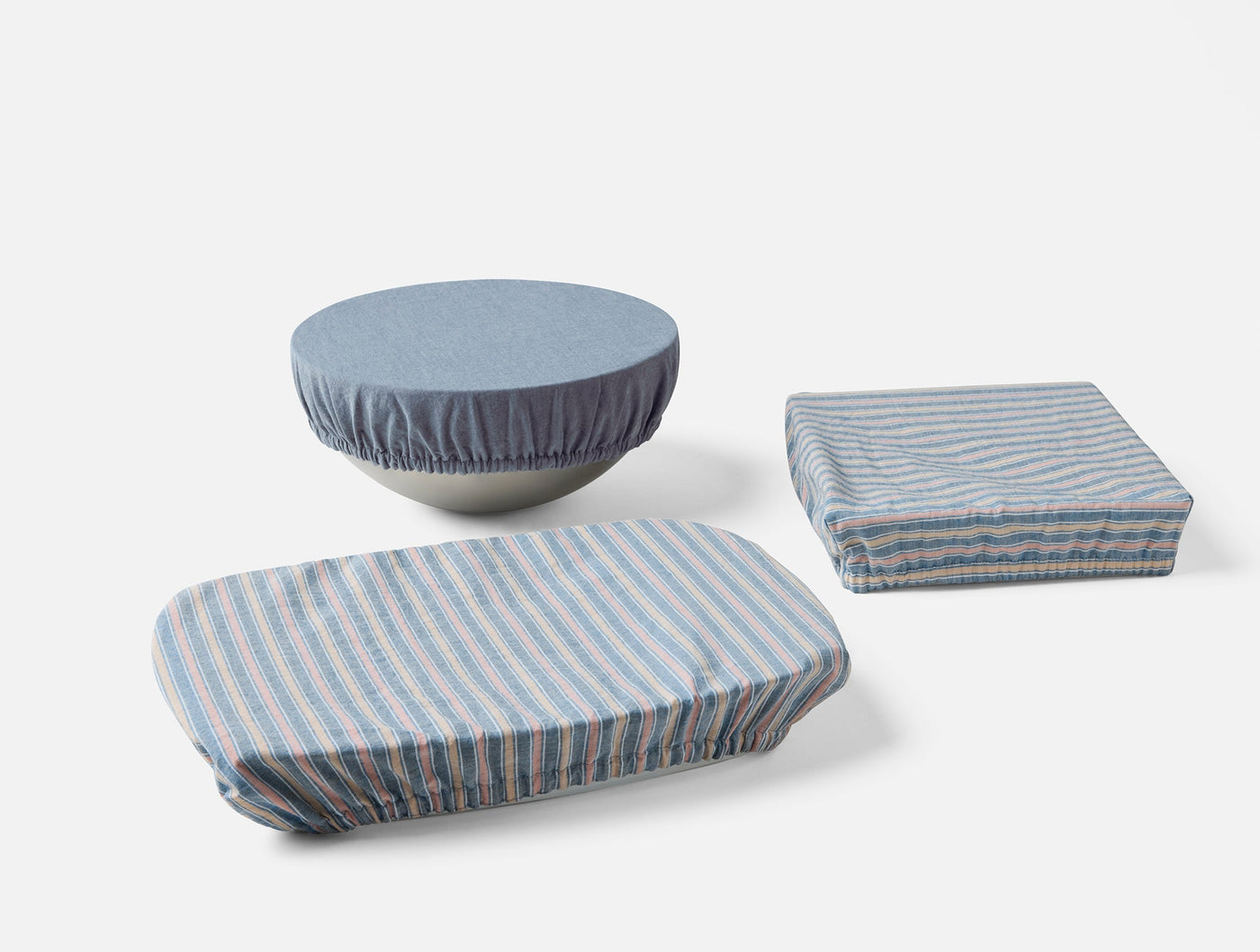 Coyuchi Conserve dish cover set in blue stripe and solid blue, styled on three dishes.
