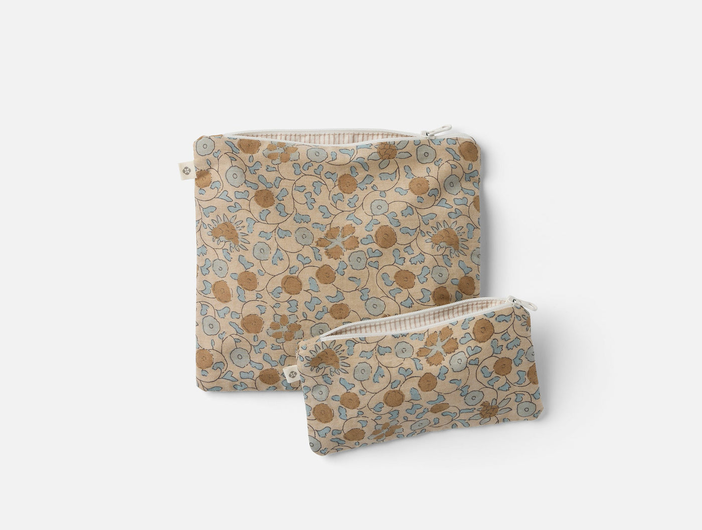 Close-up of two Coyuchi Conserve snack bags in golden floral print with zipper closure.