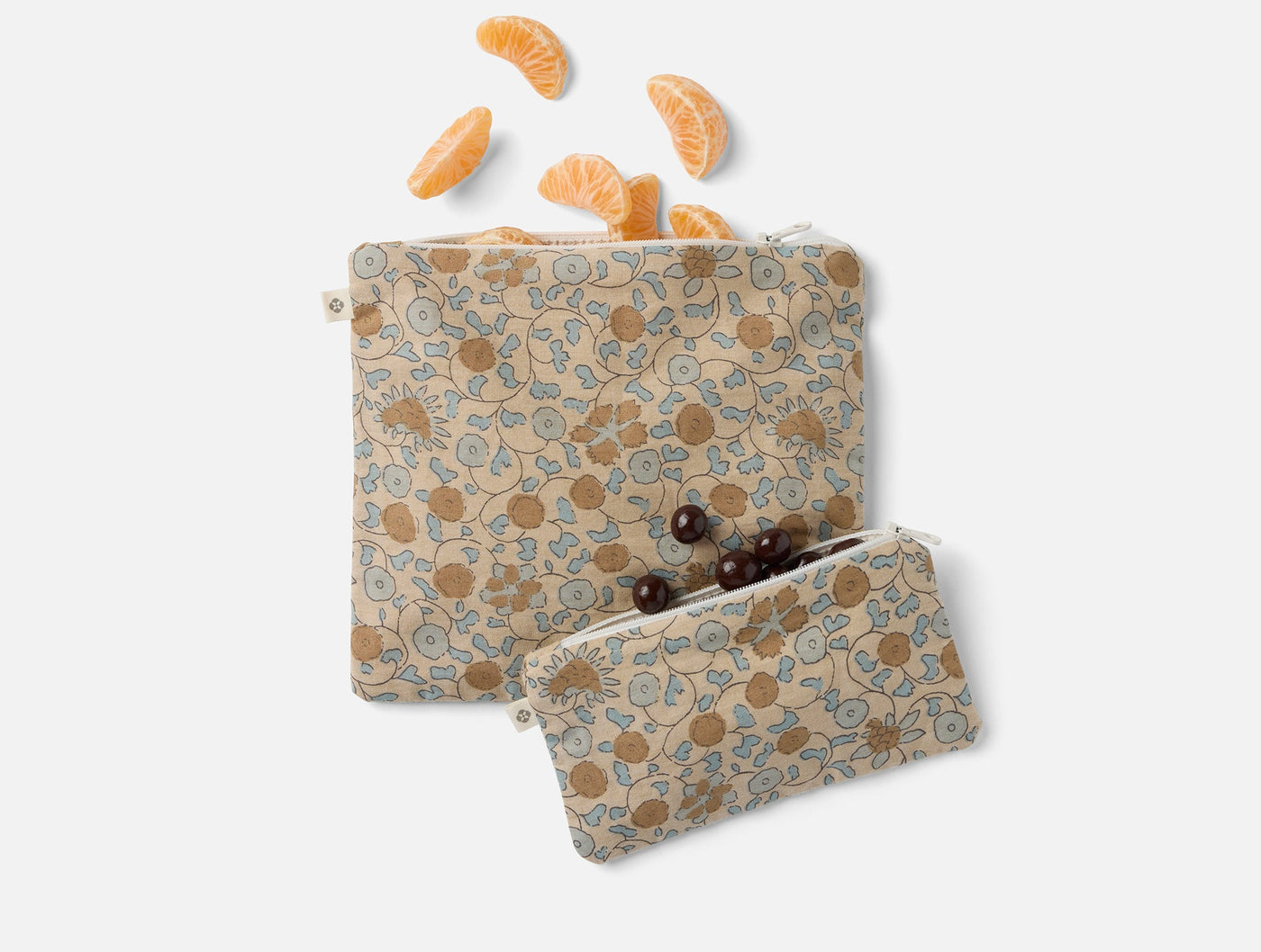 Coyuchi Conserve snack bag set styled with orange slices and chocolates, floral print.
