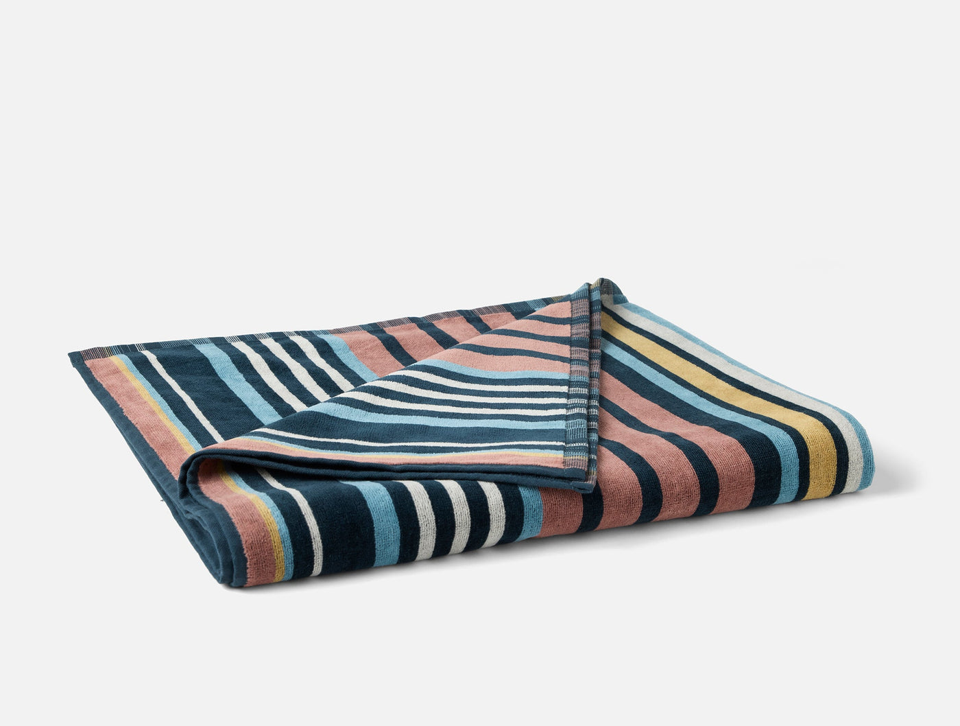 Close-up of folded Coyuchi Dawn Stripe beach towel showing multicolor stripe pattern detail.