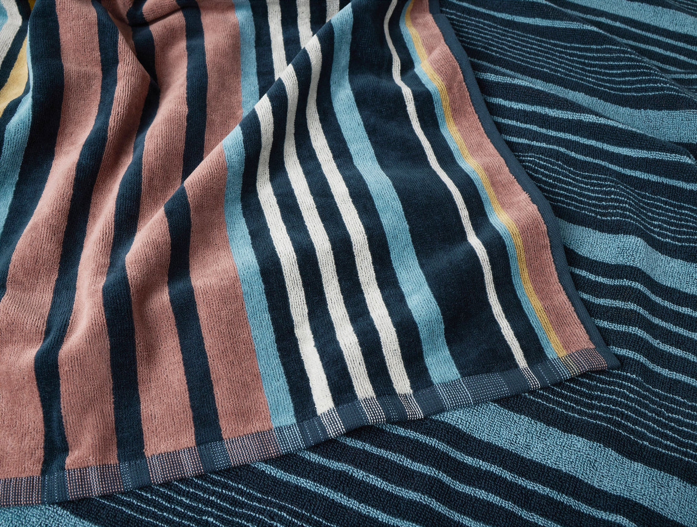 Close-up of Coyuchi Dawn Stripe beach towel hem, multicolor stripes in navy, blush, and ivory.