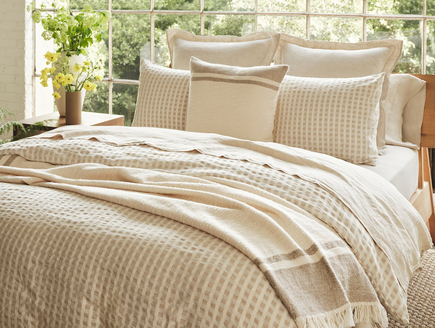 Coyuchi Birch duvet cover in natural, shown with matching pillows in sunlit bedroom.