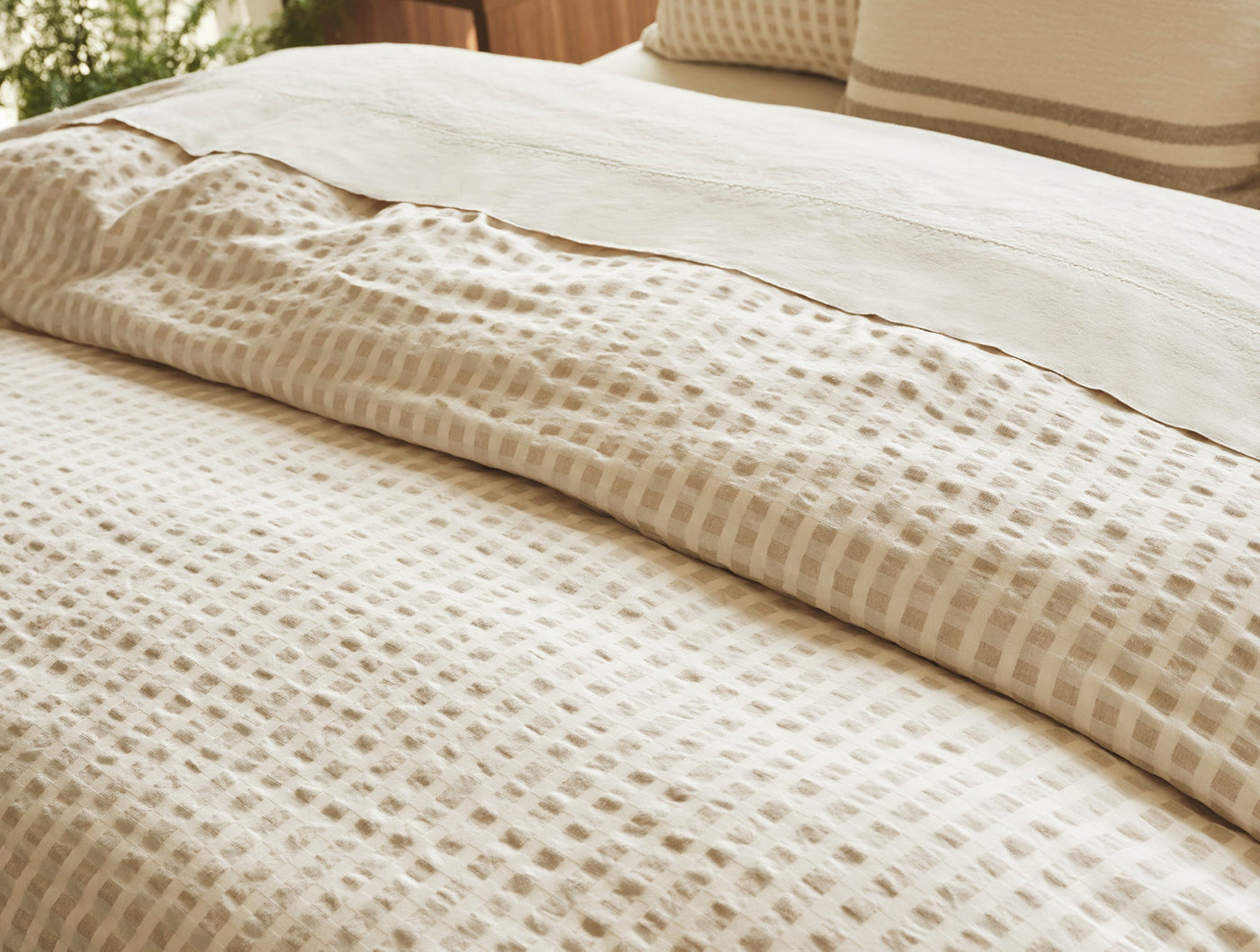 Close-up of Coyuchi Birch duvet cover showing ivory waffle-weave texture on a made bed.