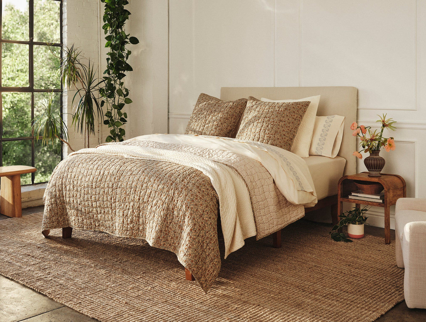 Coyuchi Angeles Matelassé blanket in warm tan draped over bed in sunlit bedroom.