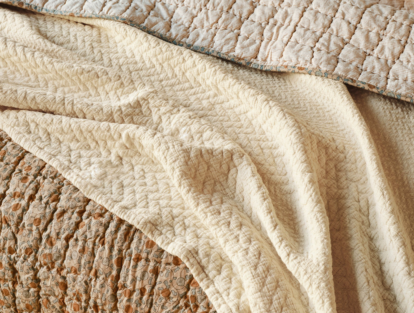 Close-up of Coyuchi Angeles Matelassé blanket in ivory, showing textured weave and soft drape.