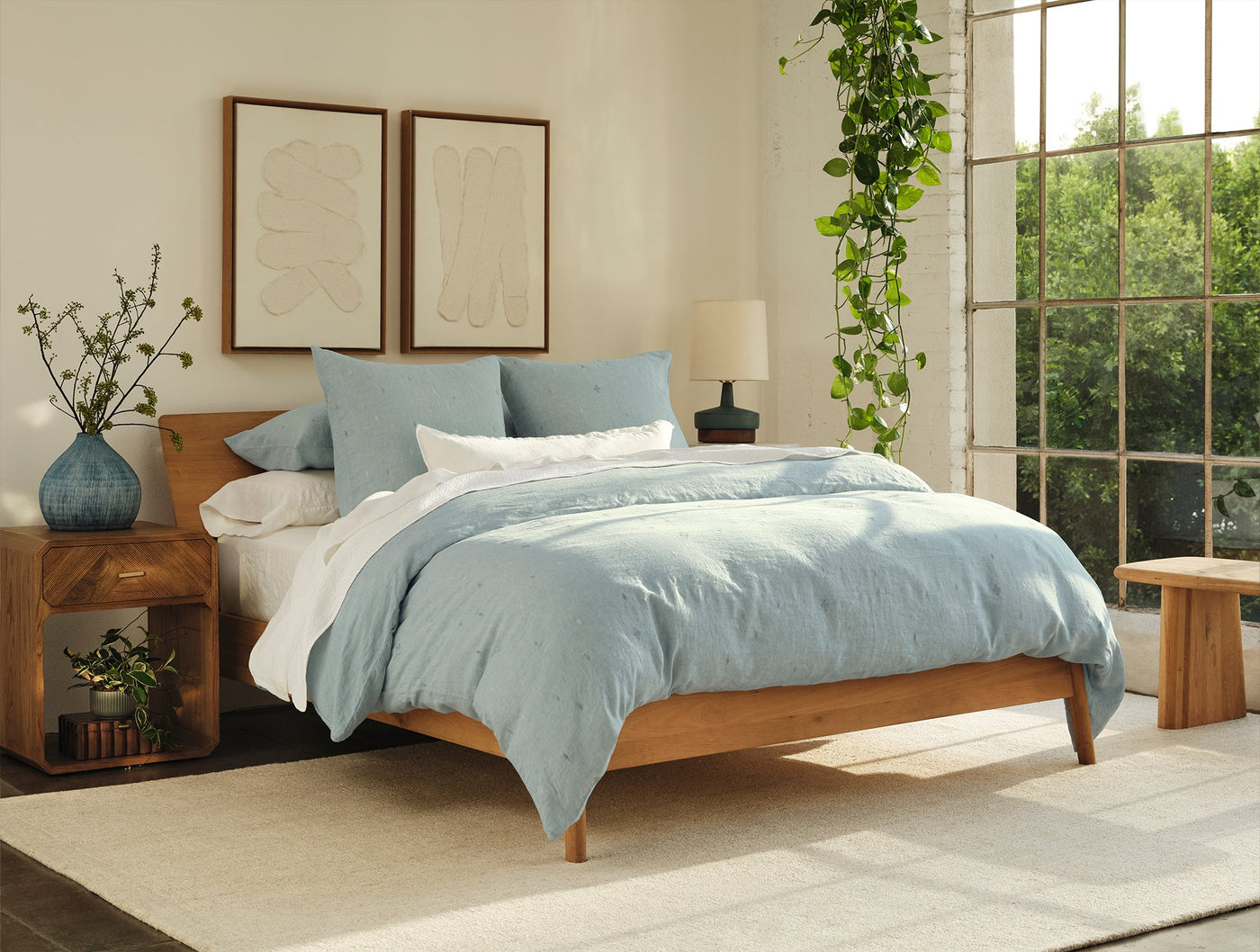 Coyuchi Cambria duvet in mist blue linen styled on a mid-century wood bed with natural light.