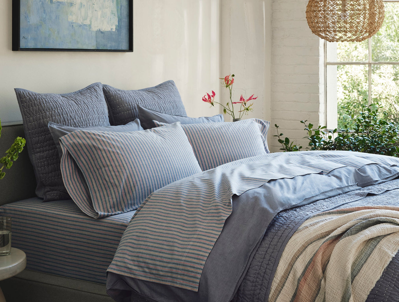 Bed styled with Coyuchi Crinkled Percale sheets in blue stripes, natural light bedroom setting.
