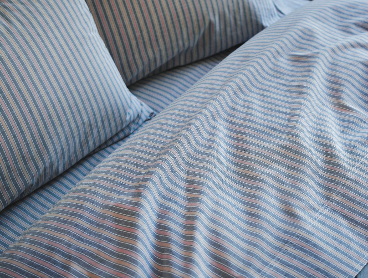 Close-up of Coyuchi Crinkled Percale pillowcase pair showing blue multistripe texture and natural drape.