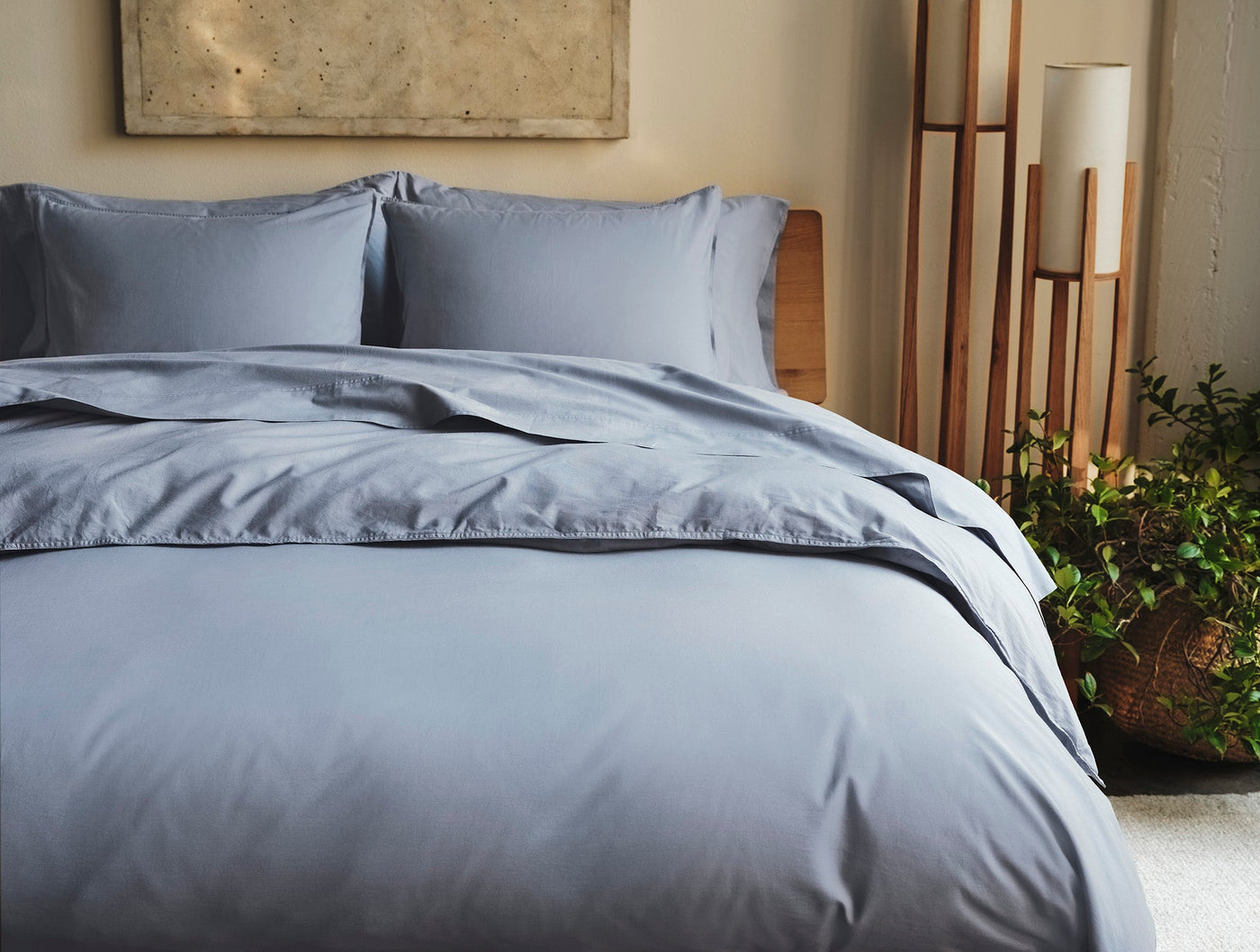 Coyuchi Crinkled Percale duvet cover in slate blue, styled on a bed with matching shams.