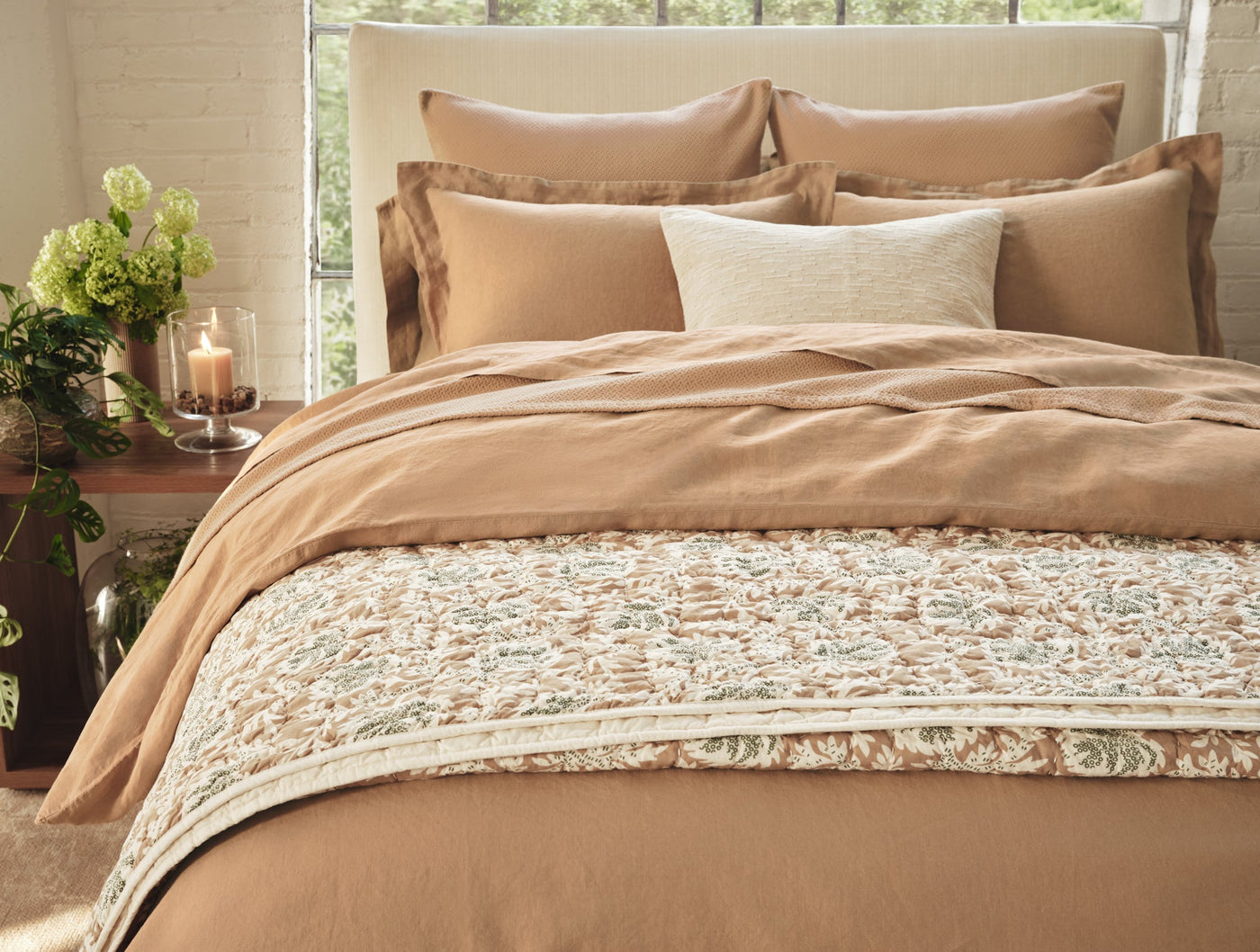 Caramel linen quilt styled on bed with floral bed scarf and layered neutral pillows.