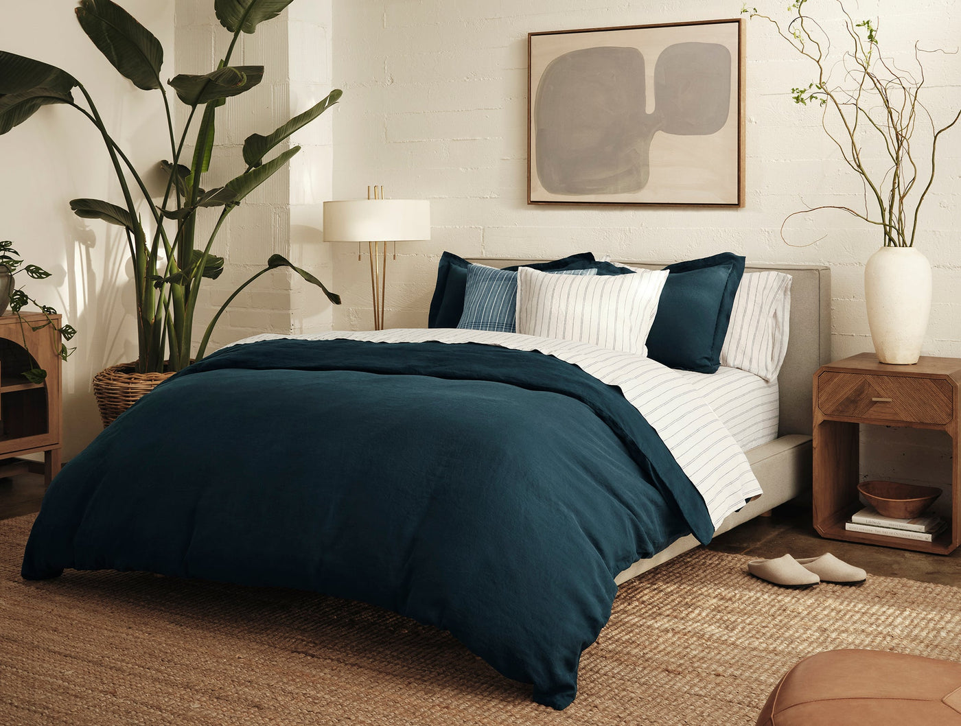 Coyuchi Relaxed Linen duvet in deep teal styled on bed with striped shams in bright bedroom.
