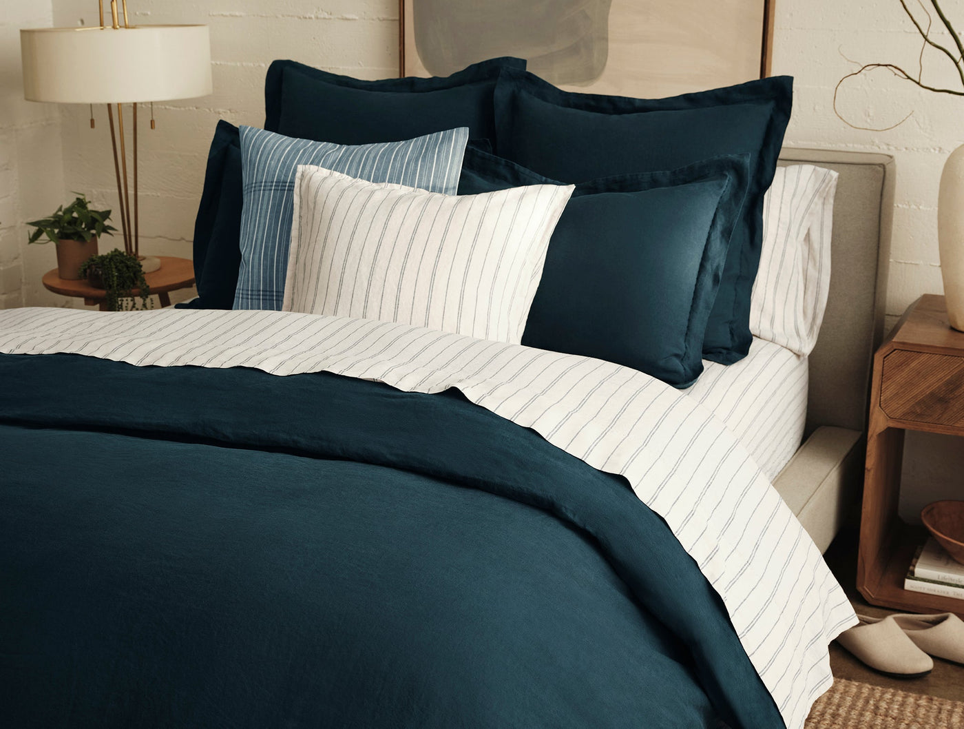 Coyuchi Relaxed Linen duvet cover in deep teal styled with striped shams on a made bed.
