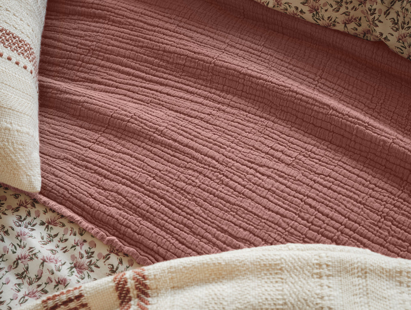 Close-up of Coyuchi Topanga Matelasse blanket in dusty rose, showing textured weave detail.
