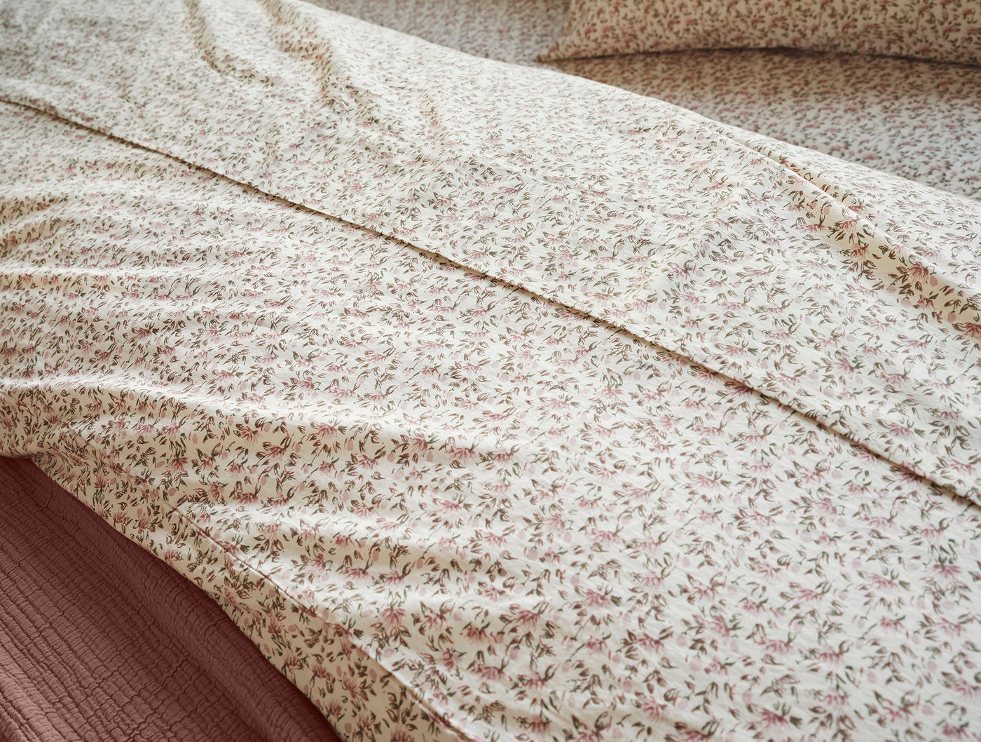 Close-up of Coyuchi Print Percale duvet cover with delicate pink floral pattern on ivory cotton.