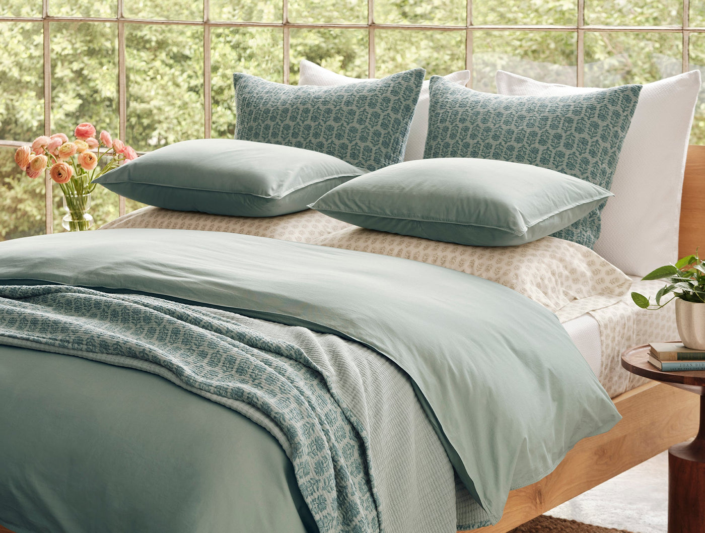 Sage green matelasse blanket draped over bed with matching pillows, geometric pattern detail visible.